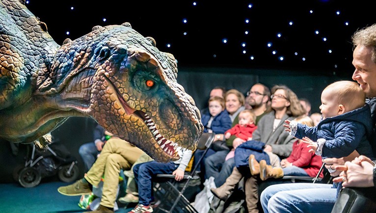 T Rex animatron in front of a group of children and adults 